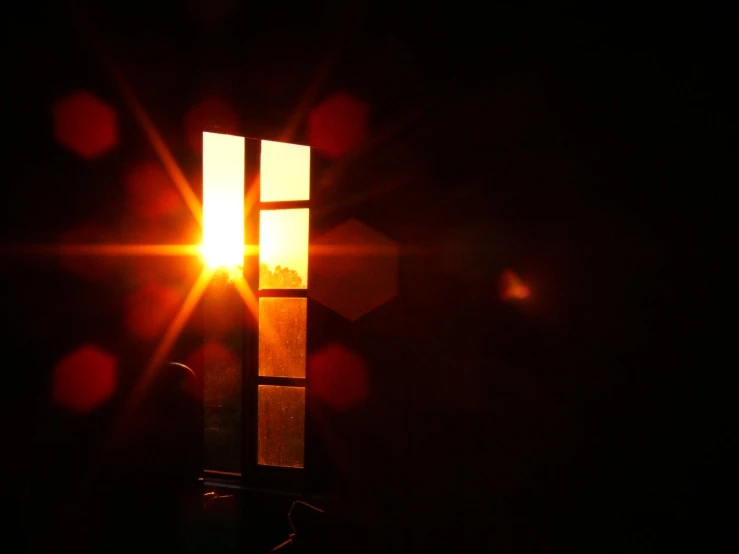 a cross in the darkness with the sun shining through