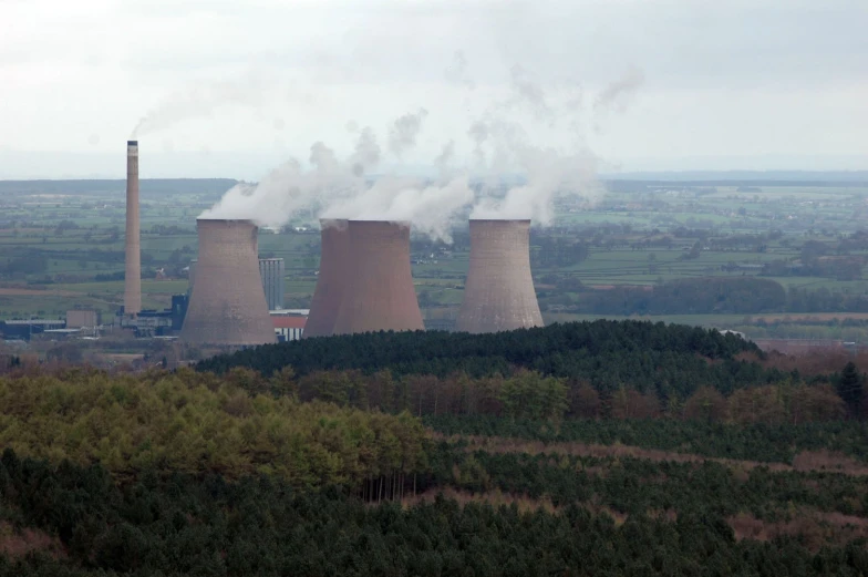 two cooling towers emitting steam in a landscape