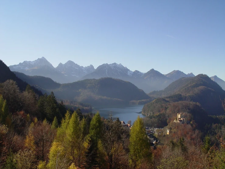 a valley view with some trees, mountains and the lake