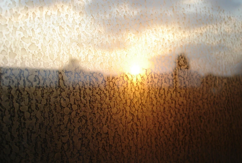 a wall with rain drops over it that has a sky background