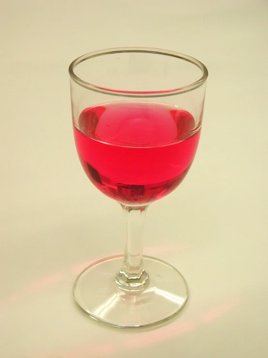 a small glass of red liquid in a round glass