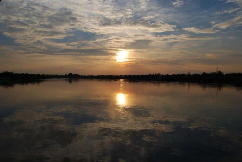 the sun rises over water with clouds in the sky