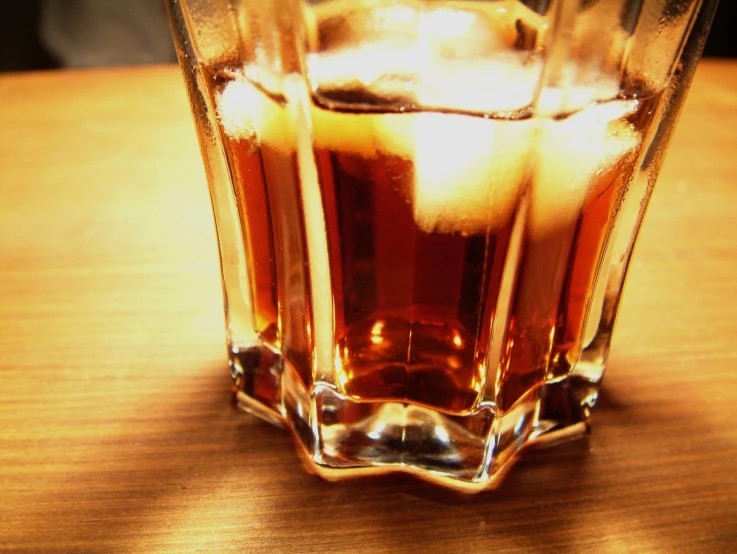 a glass sitting on a wooden table with ice