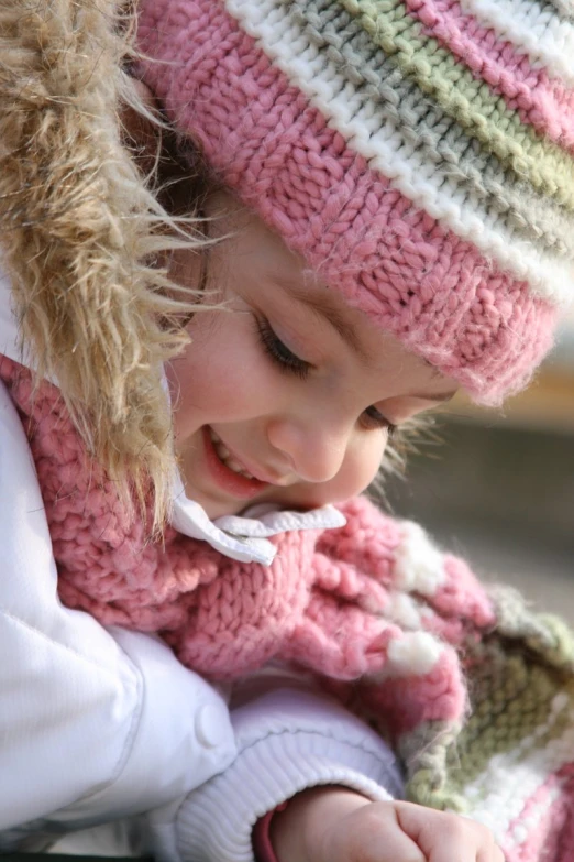 a small child in pink hat holding a cell phone