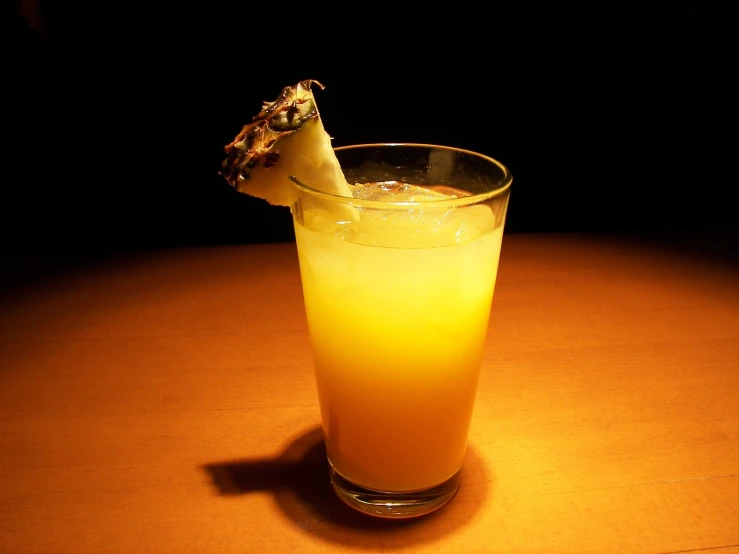 a glass with yellow liquid and an odd object on the rim