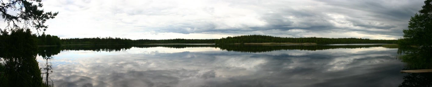 a calm lake surrounded by trees and clouds