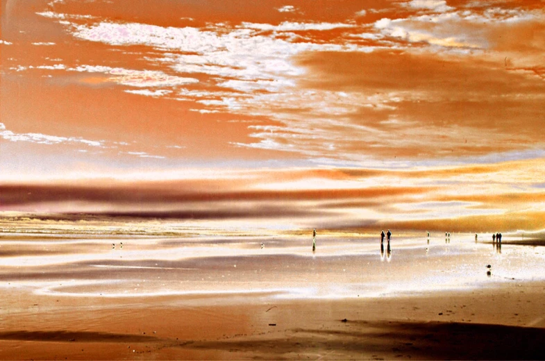 three people walk along an empty beach as the sky gets darkened
