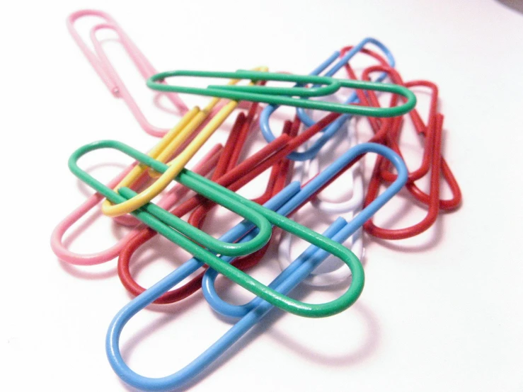 several color paper clips are arranged on a white surface