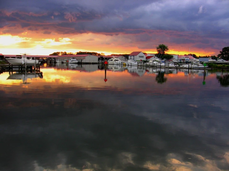 a harbor with boats and houses under a cloudy sky