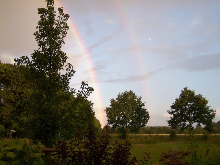 a double rainbow can be seen over the fields and woods