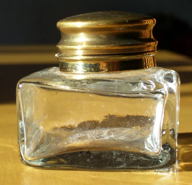 a clear square bottle with a lid sits on top of a wooden table
