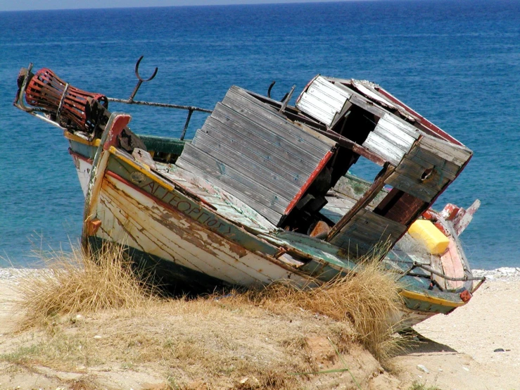 an old, run down boat in the sand near the ocean