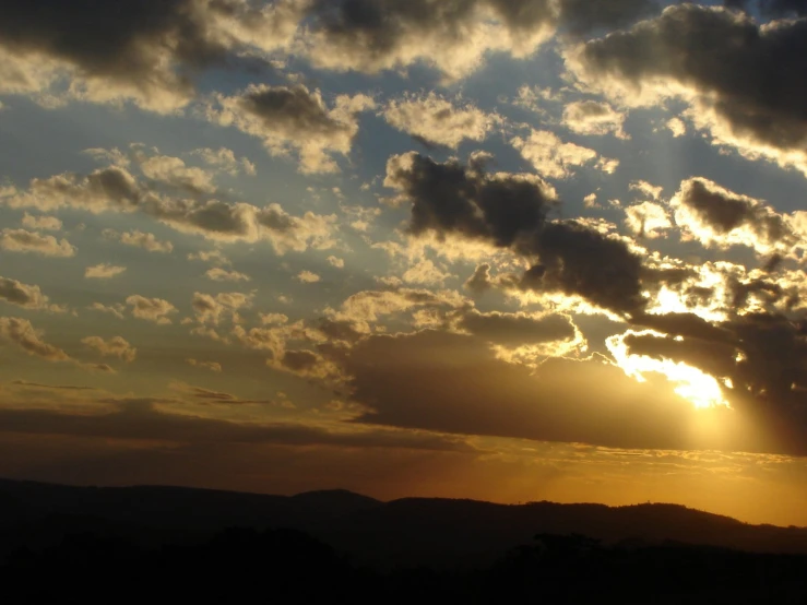 the sun peeking over a cloud covered sky