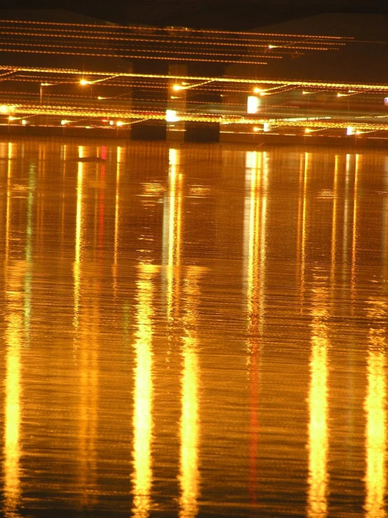 an illuminated view of a lake with boats in it at night