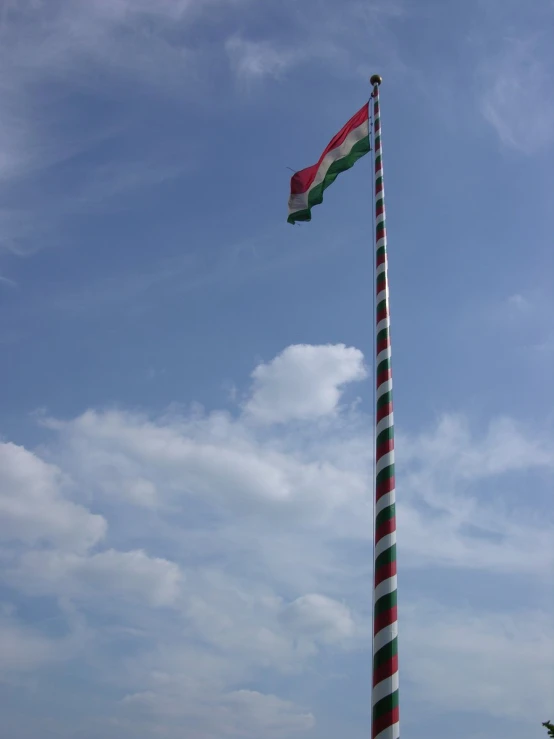 a tall red and white striped flag on top of a pole