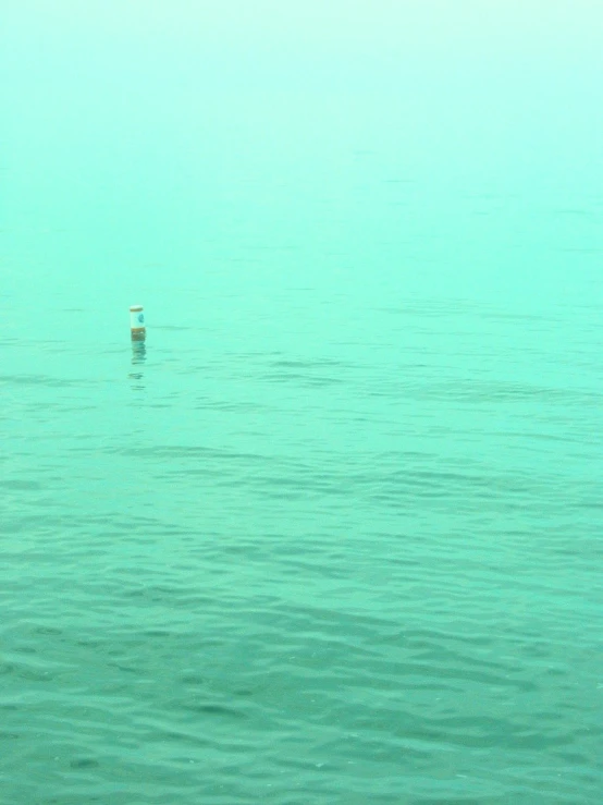 a lone boat floating in a lake next to a pier