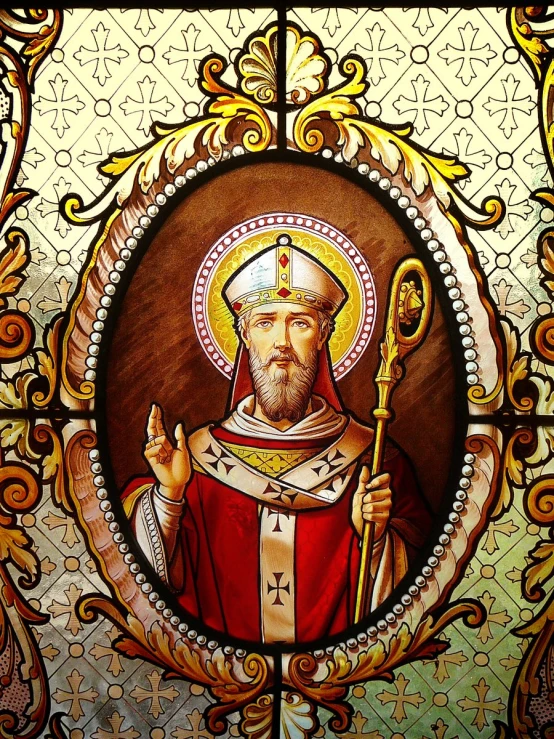 a stained glass image of a man with a golden cross and halo