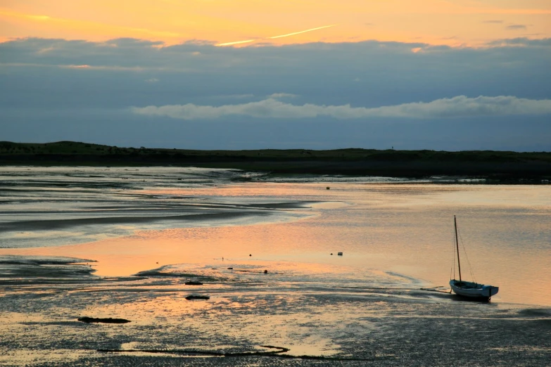 a po of a boat on the beach at sunset