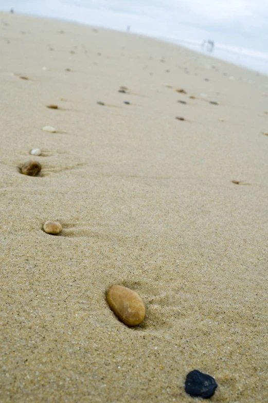 small rocks are on a sandy beach near water