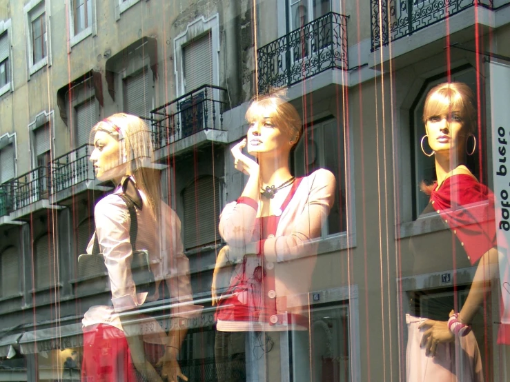 mannequins and other female outfits displayed behind glass