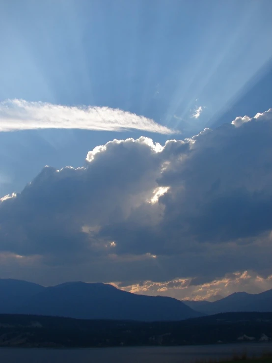 sunbeams, clouds and mountains are in the background