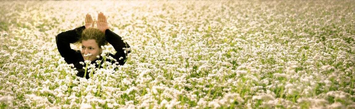 man kneeling in a large field with his hands up