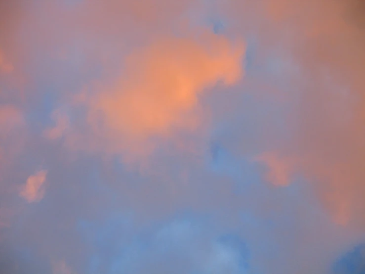 a jet is flying through the blue cloudy sky