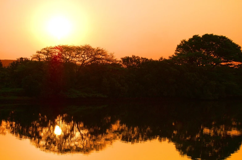 the sun is setting over a small lake