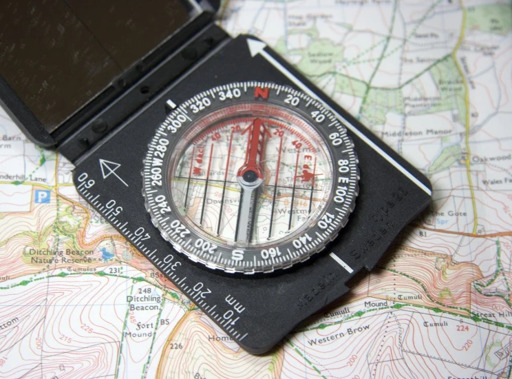 a black plastic pocket compass lying on top of a map