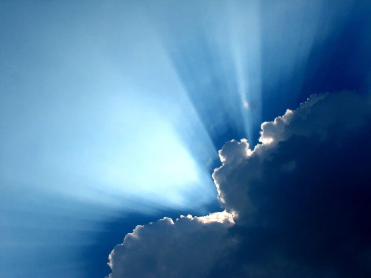 a cloud is lit by the sun through it's rays