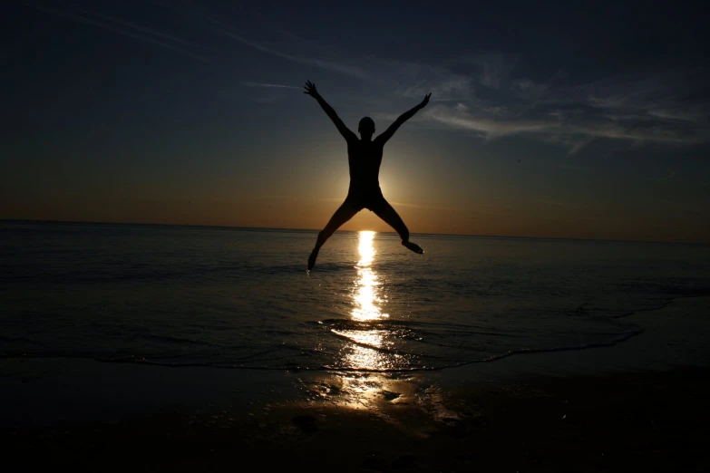 a person jumping up in the air on top of the beach