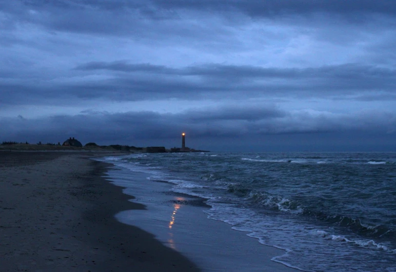 ocean with a lighthouse in the distance at night