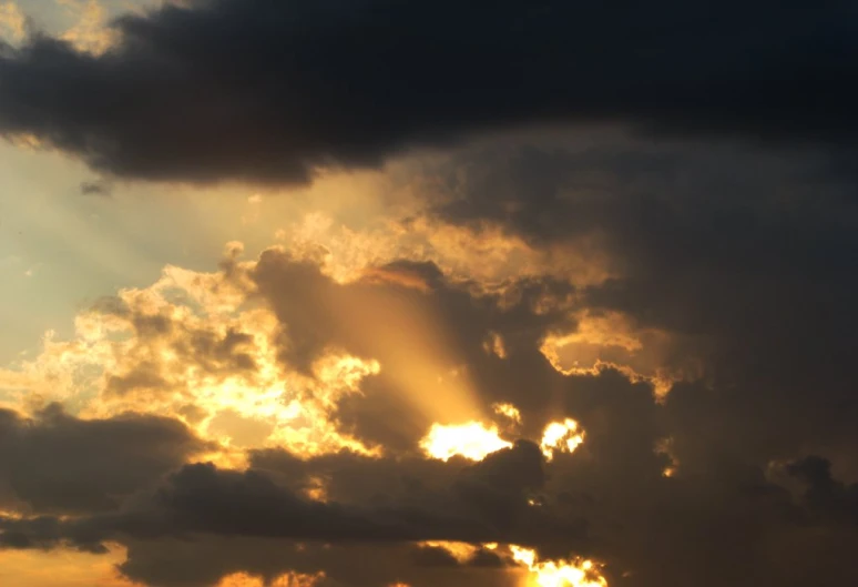 the setting sun in a cloudy sky with clouds