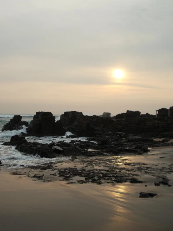 some rocks and the ocean with the sun