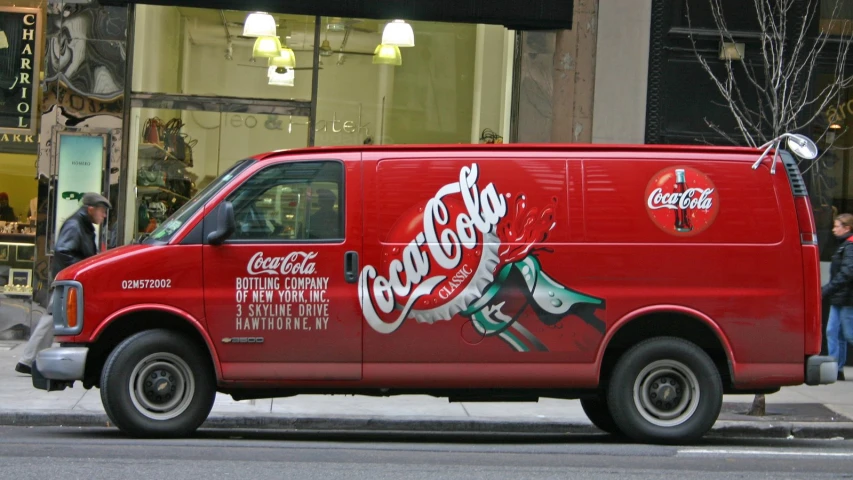 a van with coca cola painted on the side parked on a city street