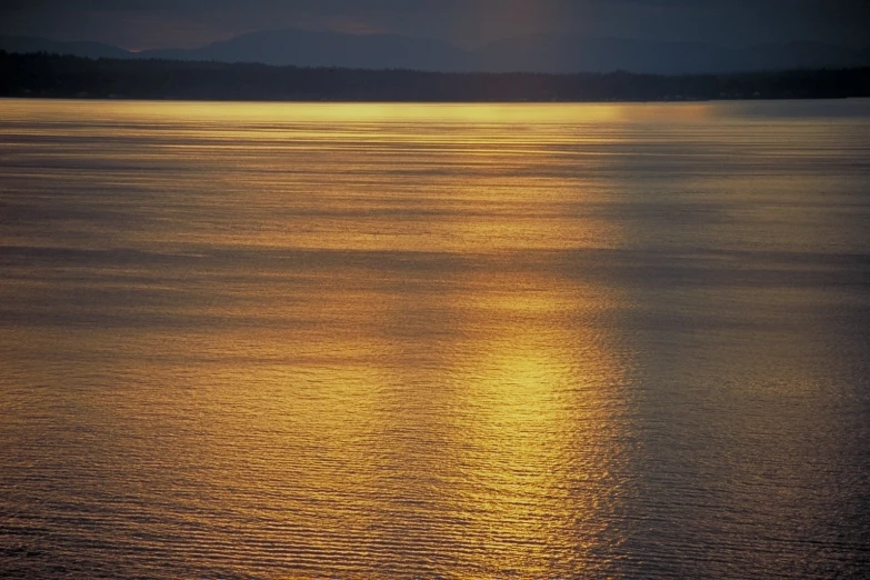 the sun reflecting off of a calm body of water