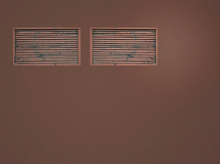 two windows with blinds are in the corner