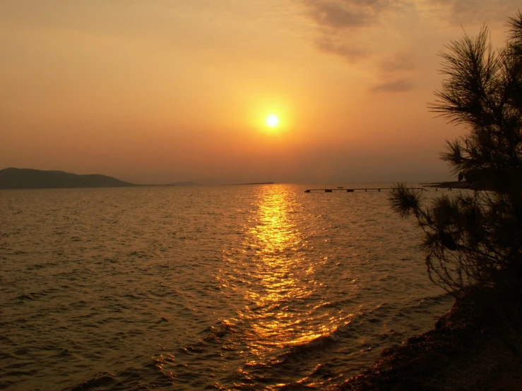 the sun rising over an empty bay with large body of water