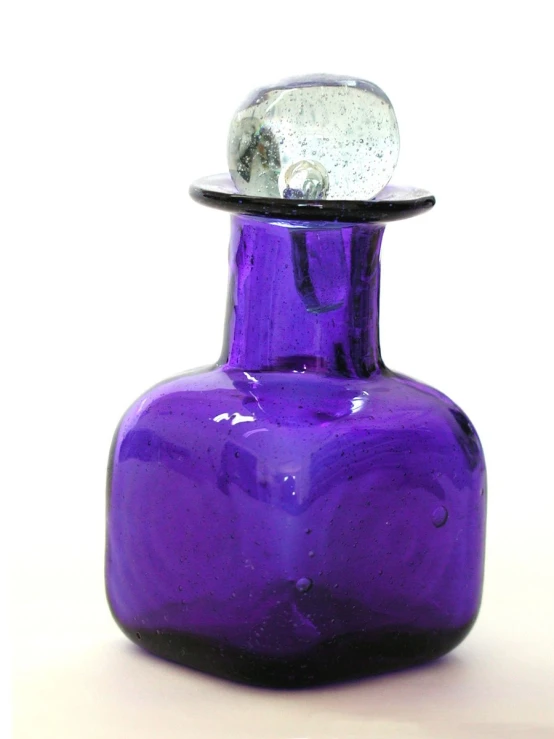 an unusual looking purple glass bottle with a white cap on top