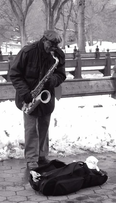 man playing on the saxophone on a city bench