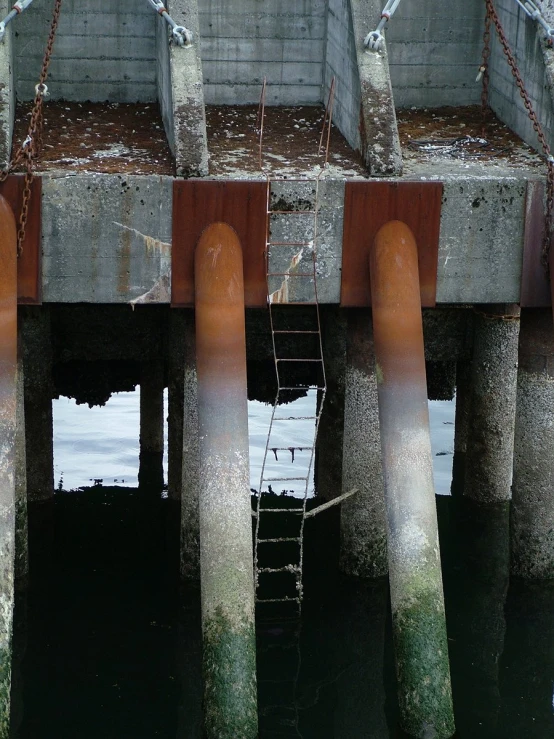 an abandoned concrete dock in water with rust colored posts