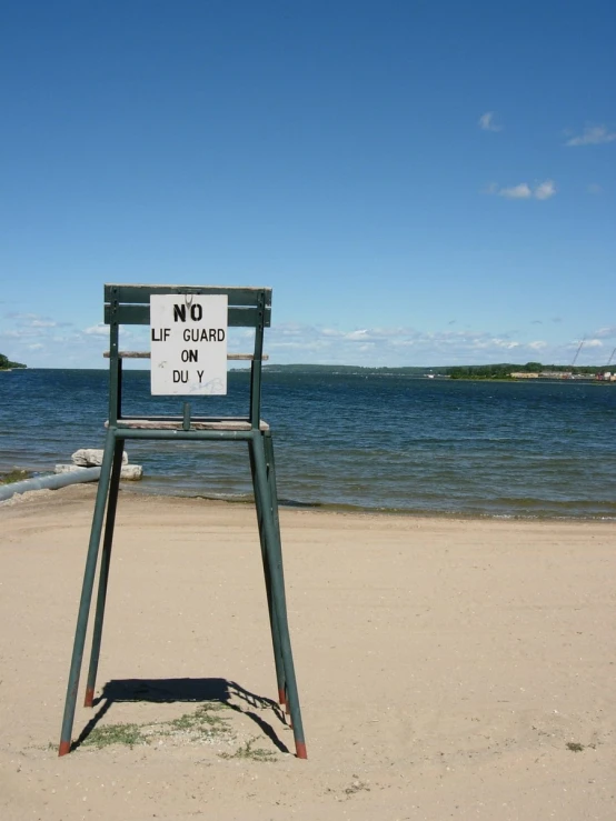 a blue chair with a sign in it near the water