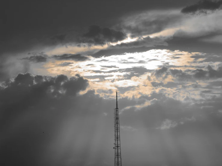 a very tall tv tower with lots of clouds around it