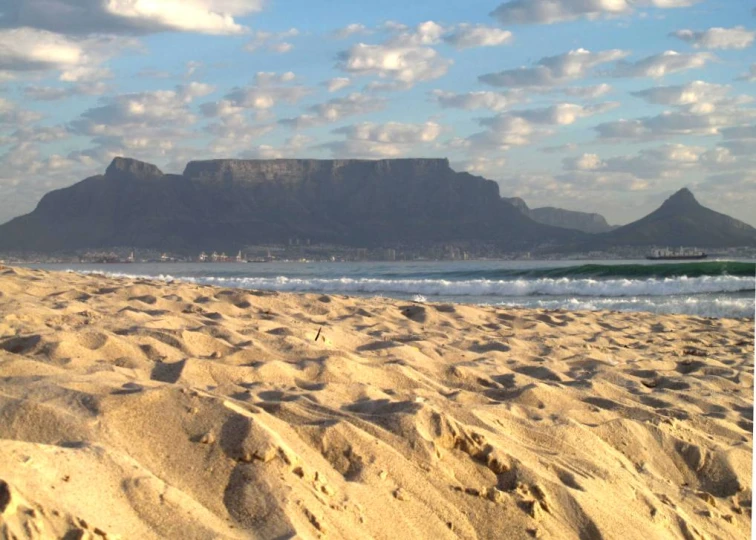 there is a sandy beach and table mountain in the background