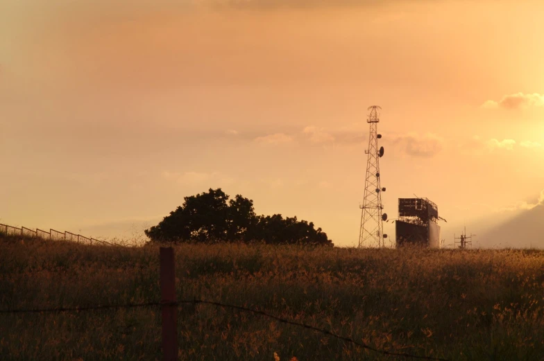 a windmill sits above a field of tall grass