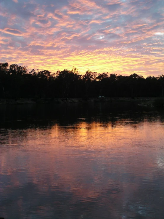 a beautiful sunset with white clouds reflecting off of the water