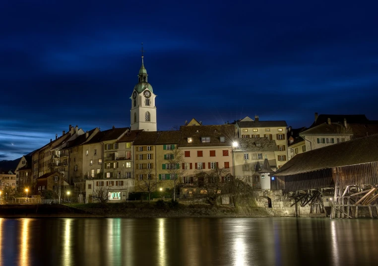 the clock tower is seen across a body of water