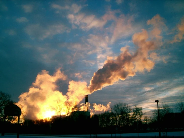 smokestacks emit from factories at sunset
