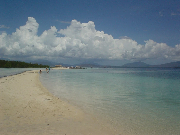 people on the beach in front of clear blue water