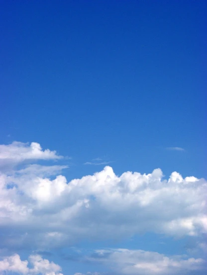 a plane is flying through the air under a cloud filled blue sky